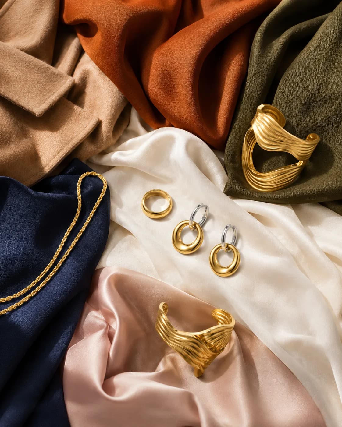 Camel, rust, olive, cream, navy and blush fabrics with gold and two tone pieces laid across them
