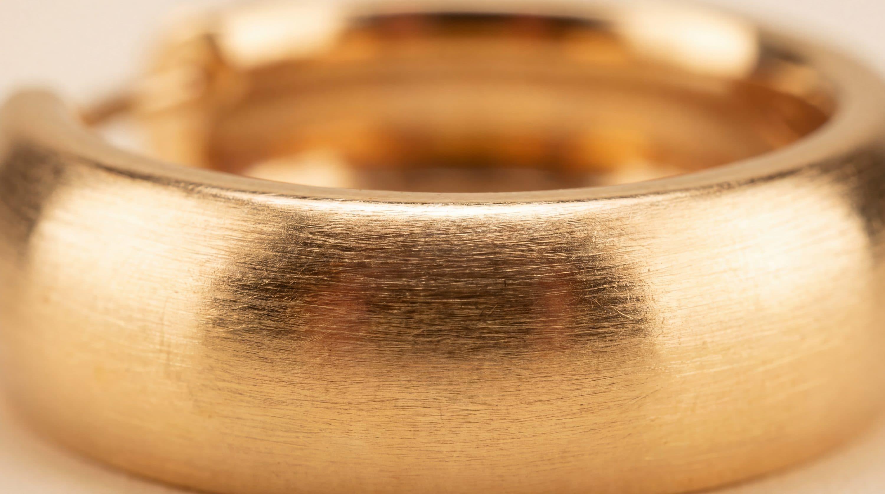 A gold hoop earring photographed close up against a plain background